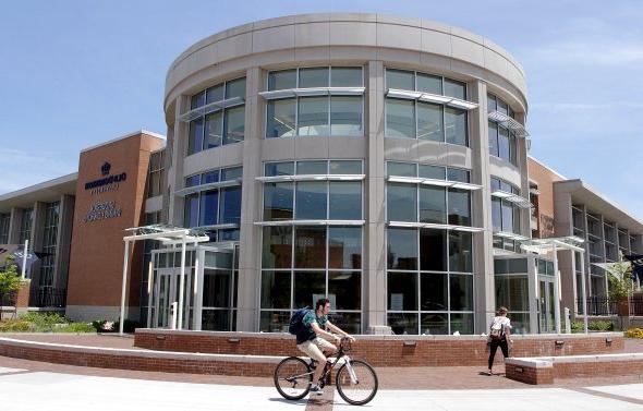 Student riding a bike in front of Broderick 餐厅 Commons